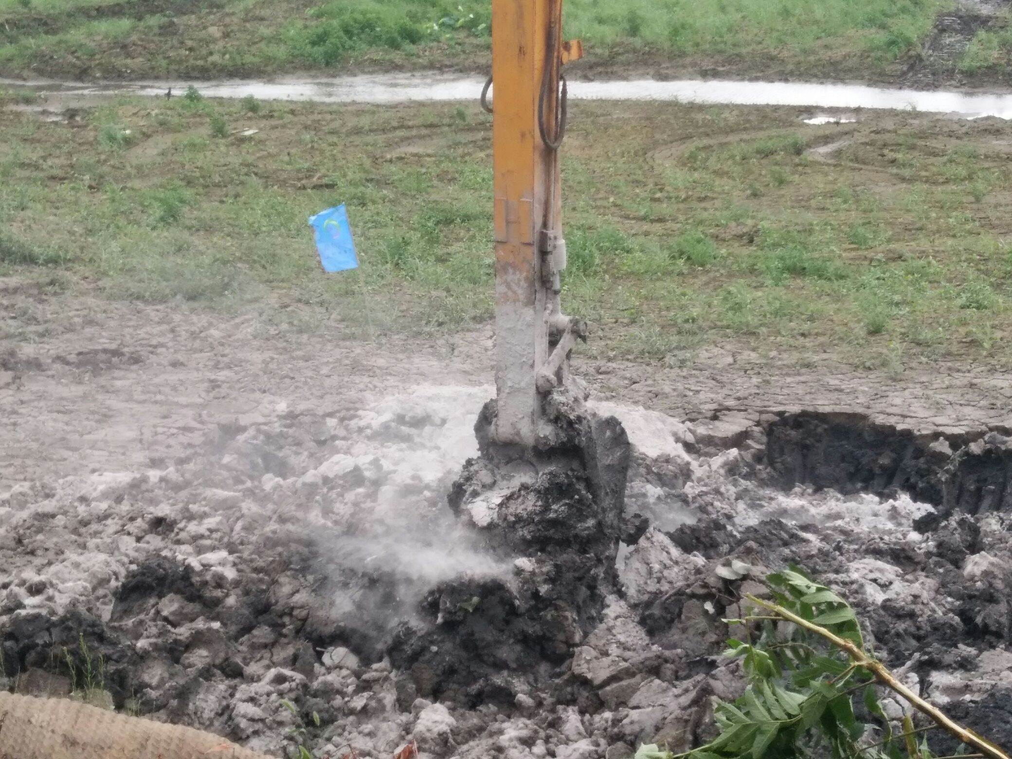 一台挖机开始将淤泥和“纯碱”拌和